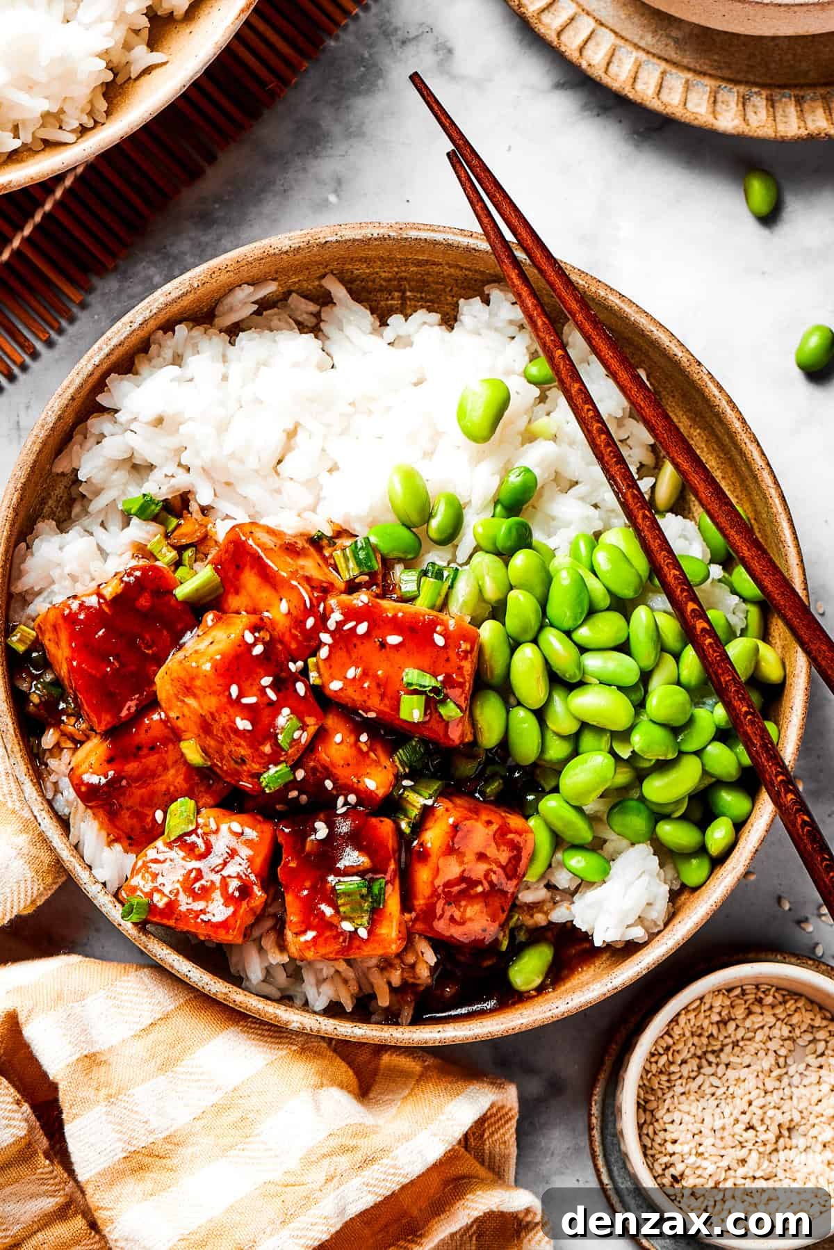 A bowl of white rice topped with cubed salmon and edamame.