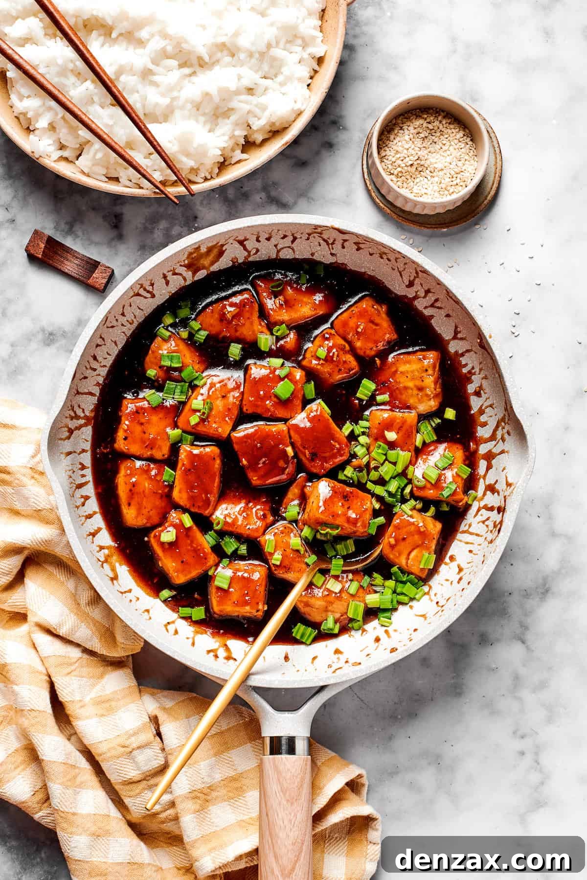 A skillet of teriyaki salmon and a bowl of rice.