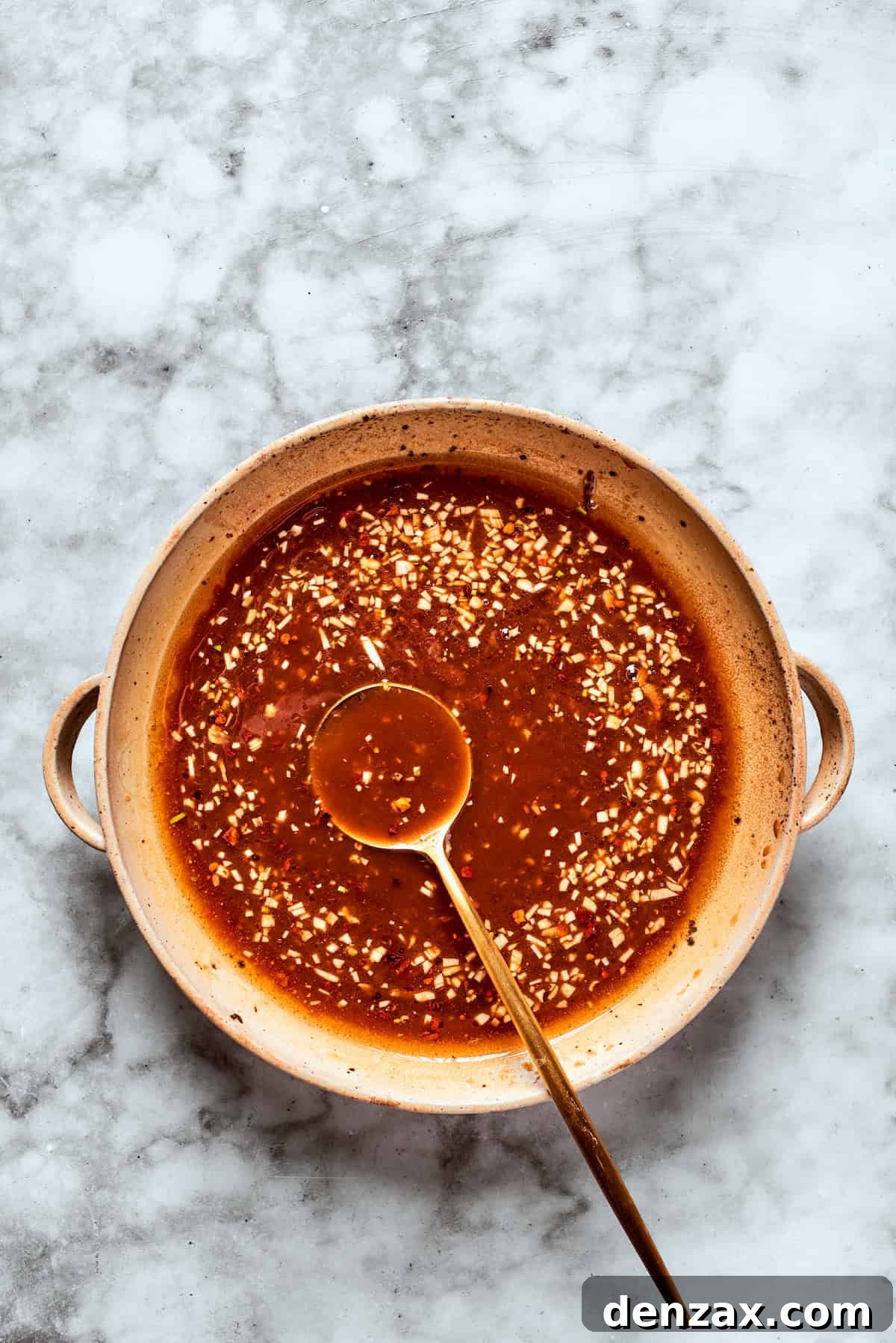 A spoon in a bowl of teriyaki sauce.