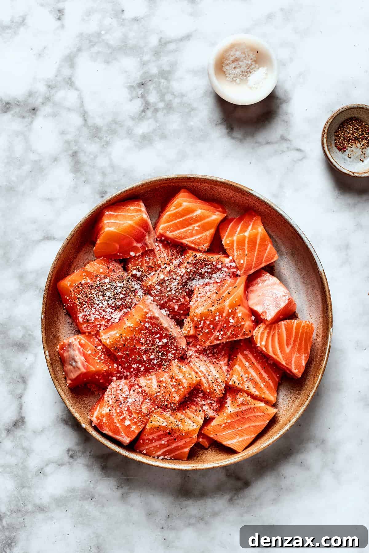 Salt and pepper season cubes of salmon.