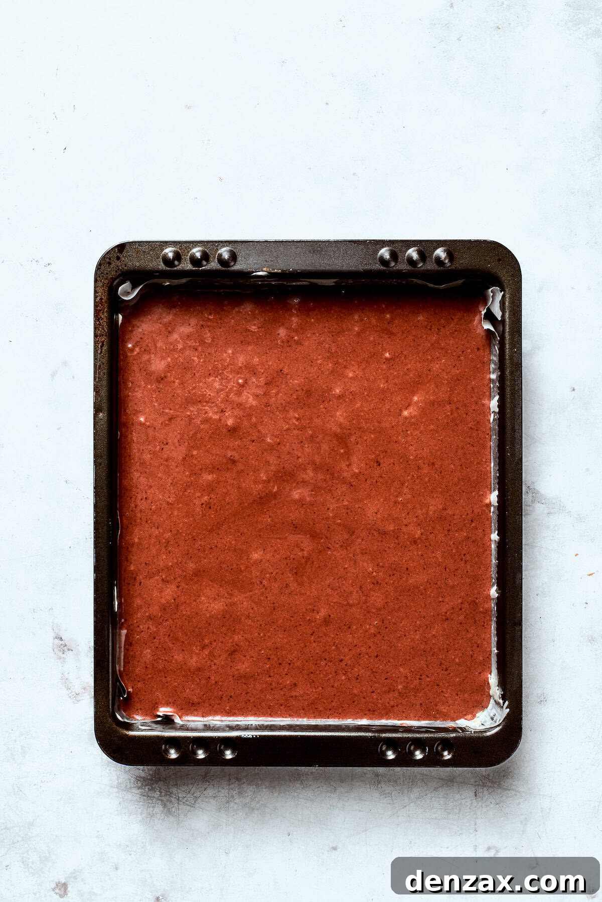 Chocolate cake batter in a cake tin.