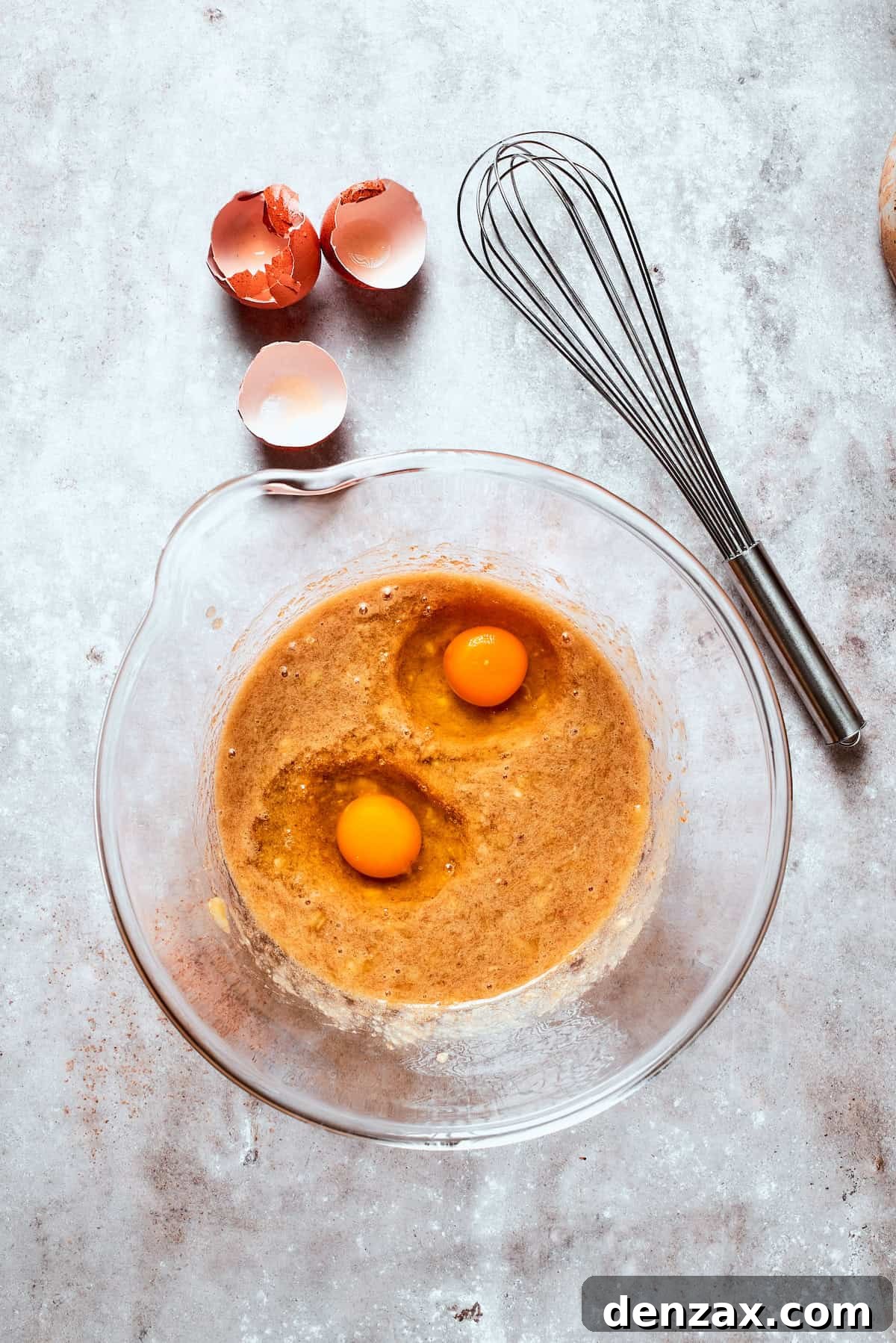 Two eggs are added to banana bread batter.