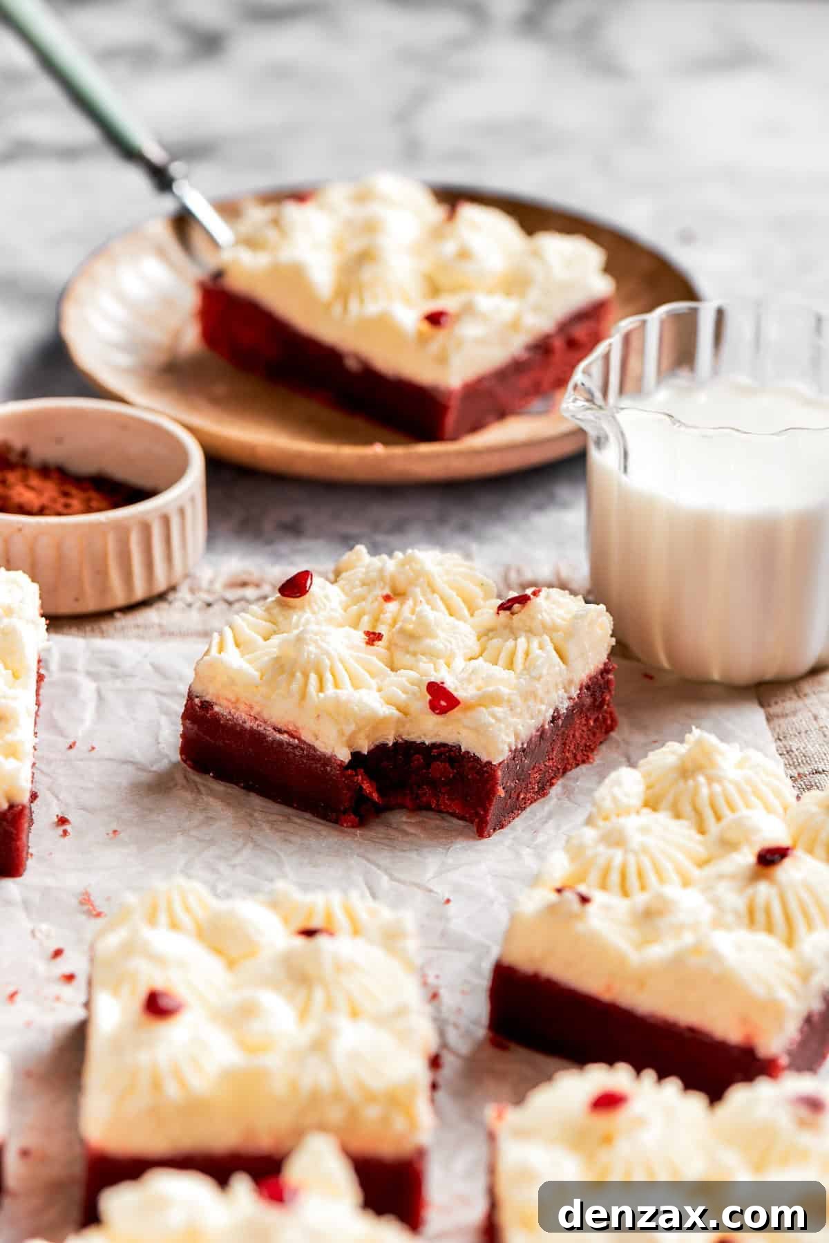A red velvet brownie with a bite taken out and a glass of milk.