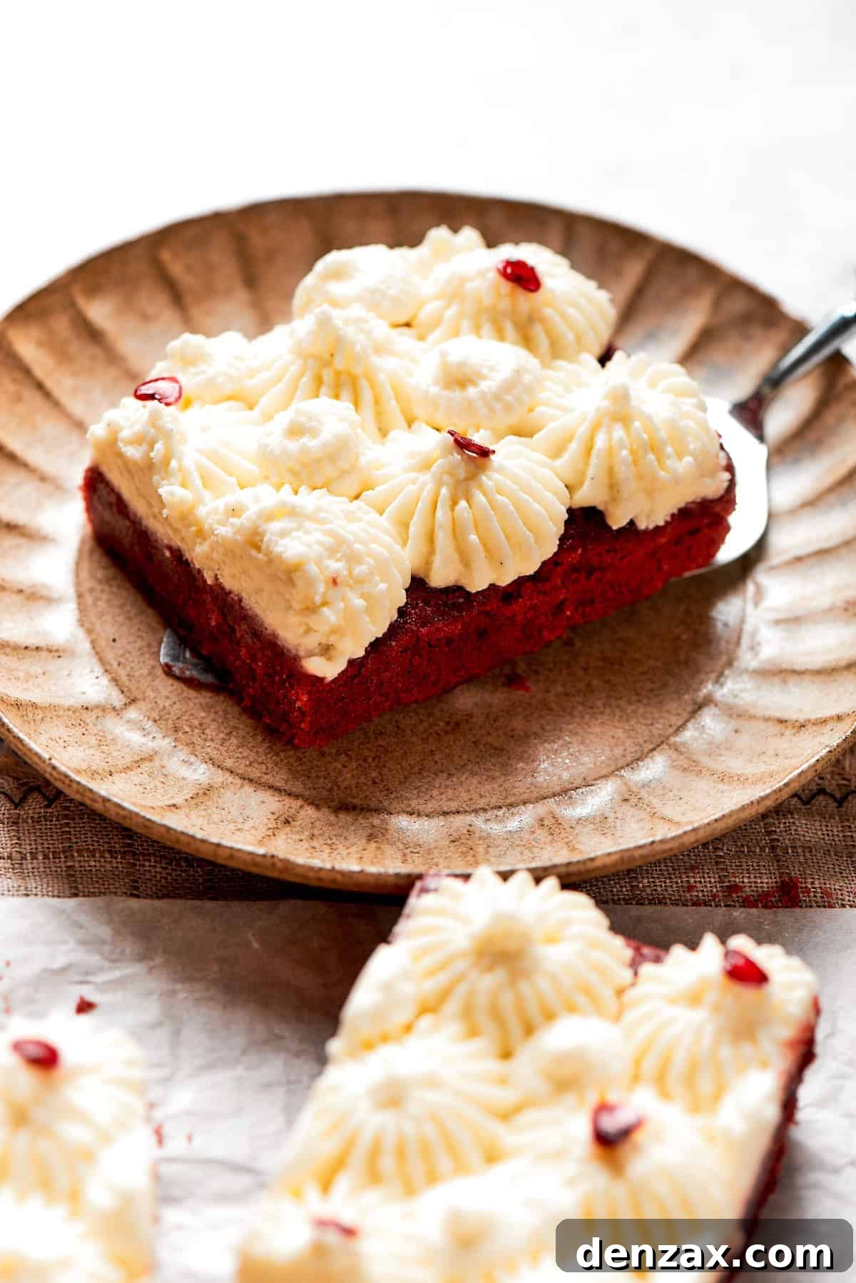 A red velvet brownie with frosting on a plate.