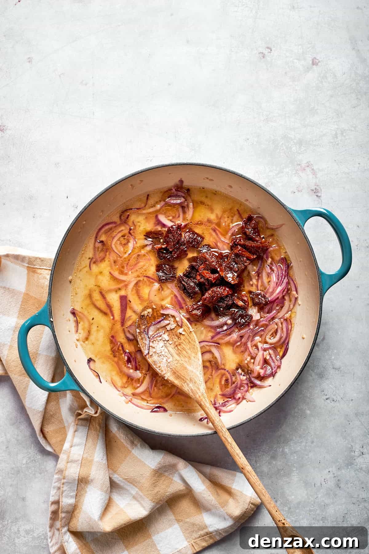 Sundried tomatoes are stirred into a skillet.