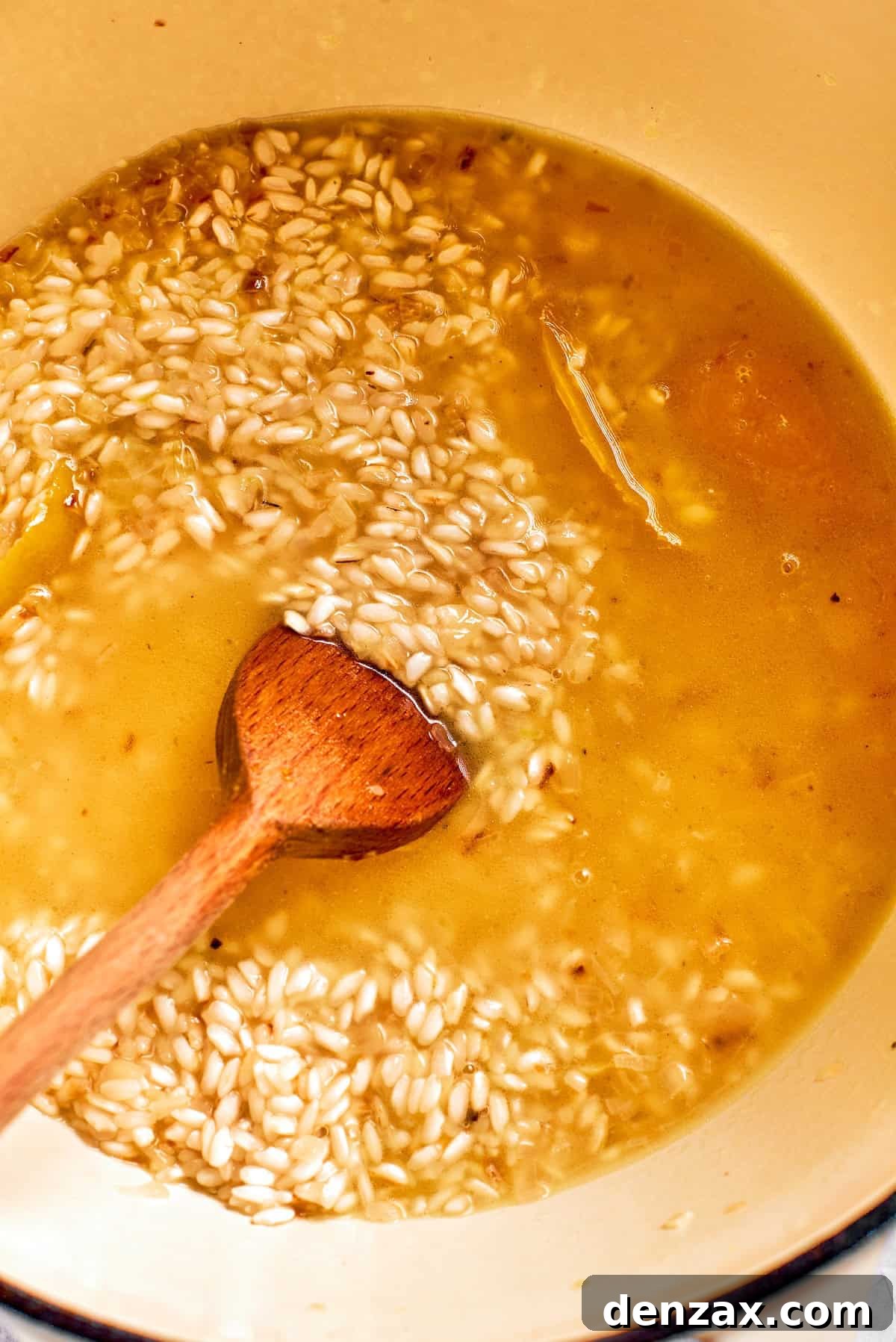 Broth is stirred into risotto rice.