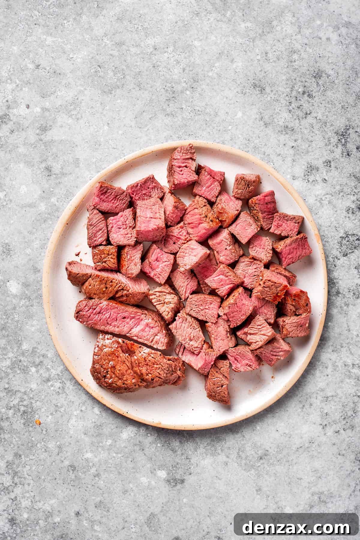 Pieces of cooked steak on a plate.
