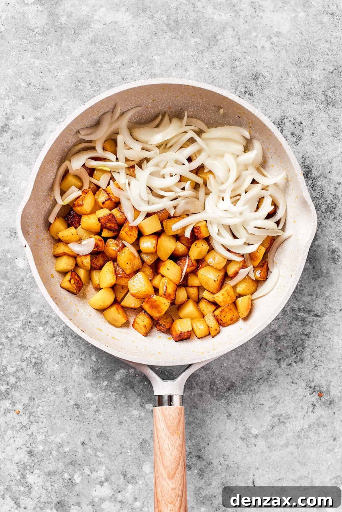 Potatoes and sliced onions in a skillet.