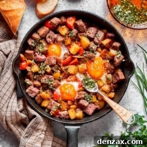A cast iron skillet full of steak and eggs and a spoon.