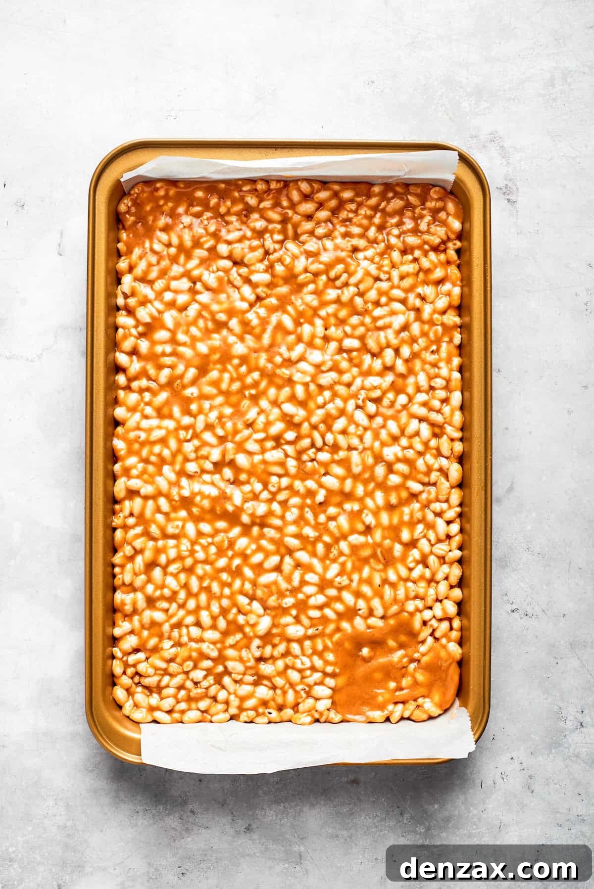Scotcharoos base pressed into a baking pan.