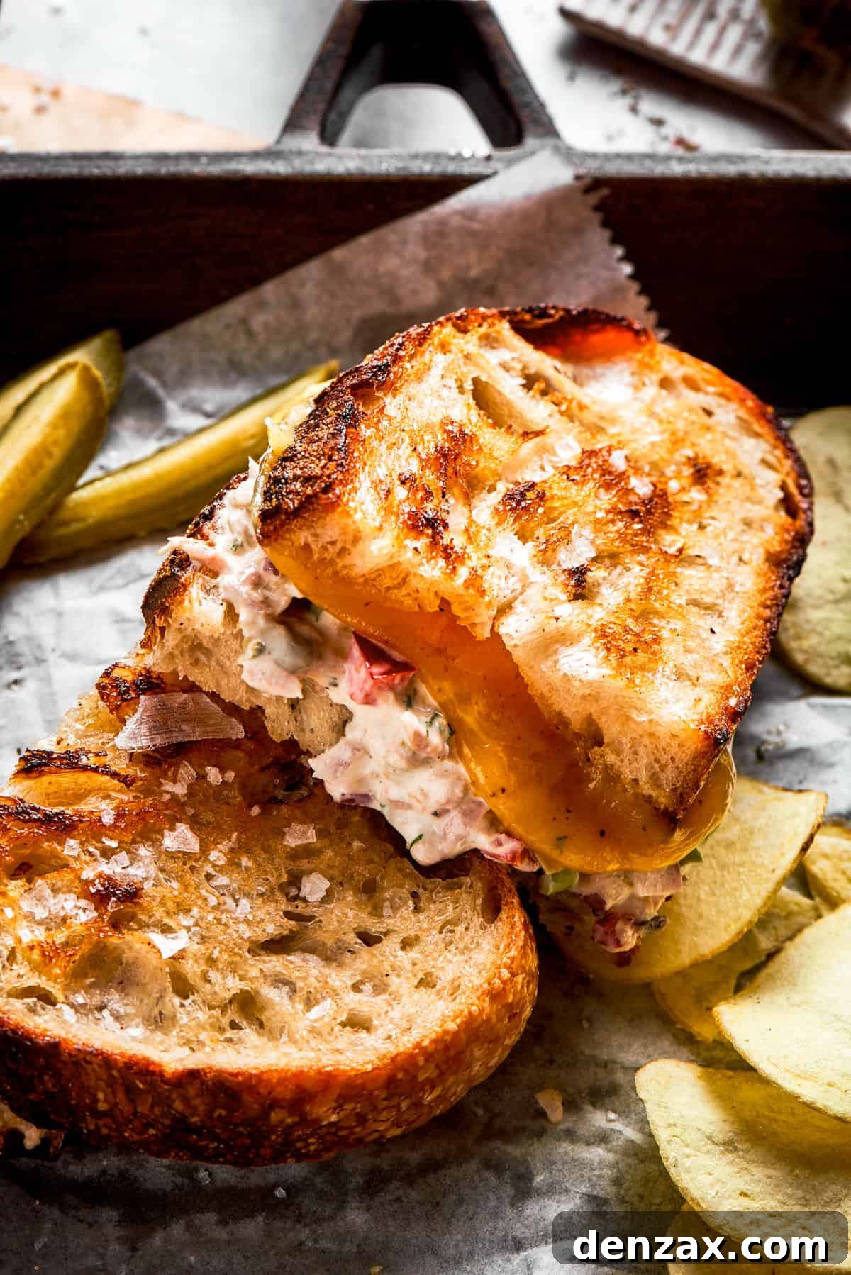 Two sandwiches filled with tuna salad and melty cheese.