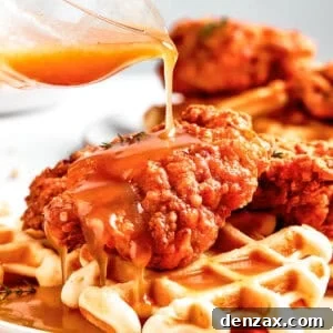 Pouring sauce over waffles and fried chicken.