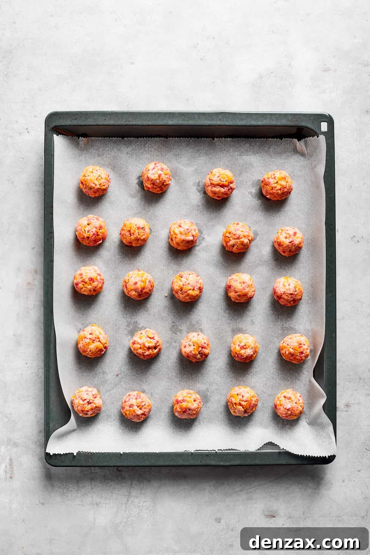 This sausage balls recipe relies on Bisquick, pork sausage, and Italian seasoning for an easy appetizer. Don't forget the dipping sauce! A lined baking tray with sausage balls.