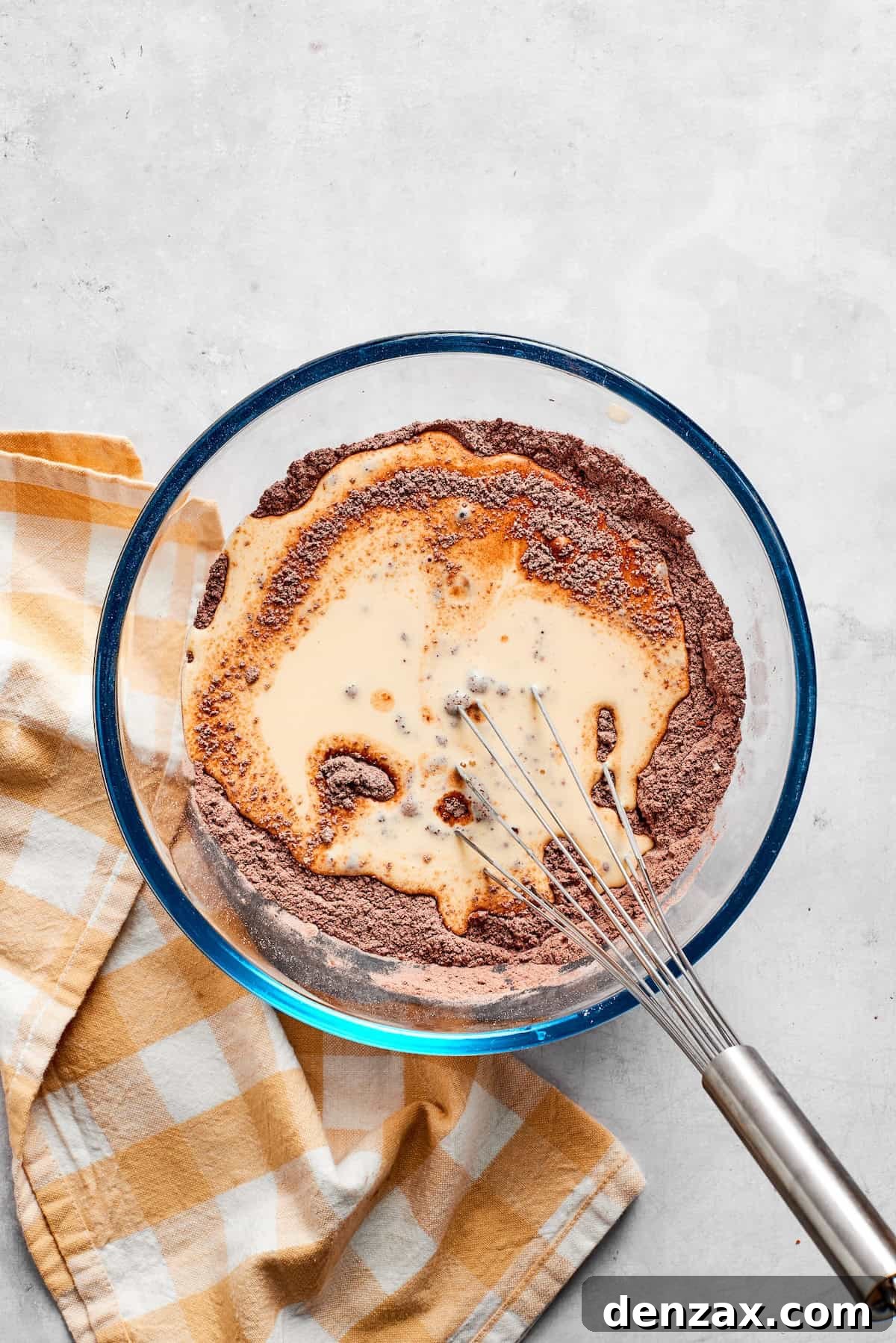 Dry and wet ingredients for chocolate muffins are whisked together in a bowl.