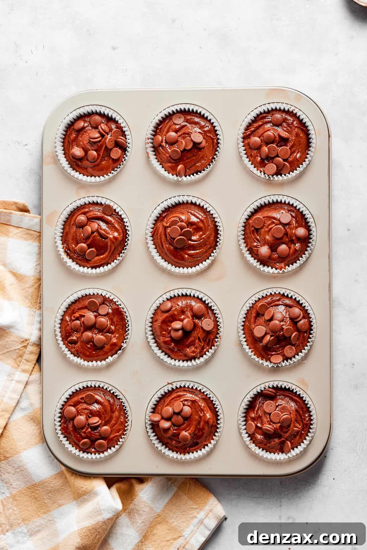 Chocolate muffin batter is divided into a muffin tin.