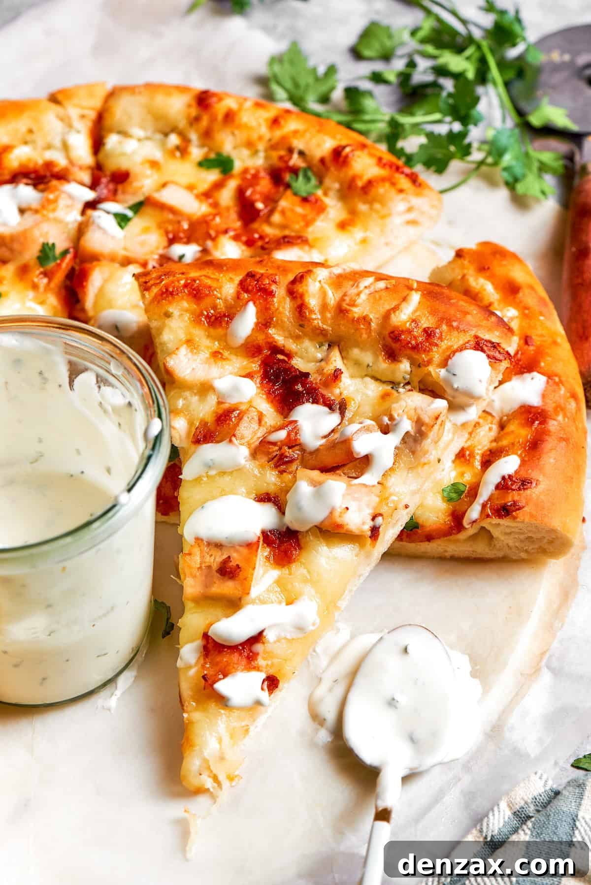 Ranch sauce is drizzled on a slice of chicken bacon ranch pizza.