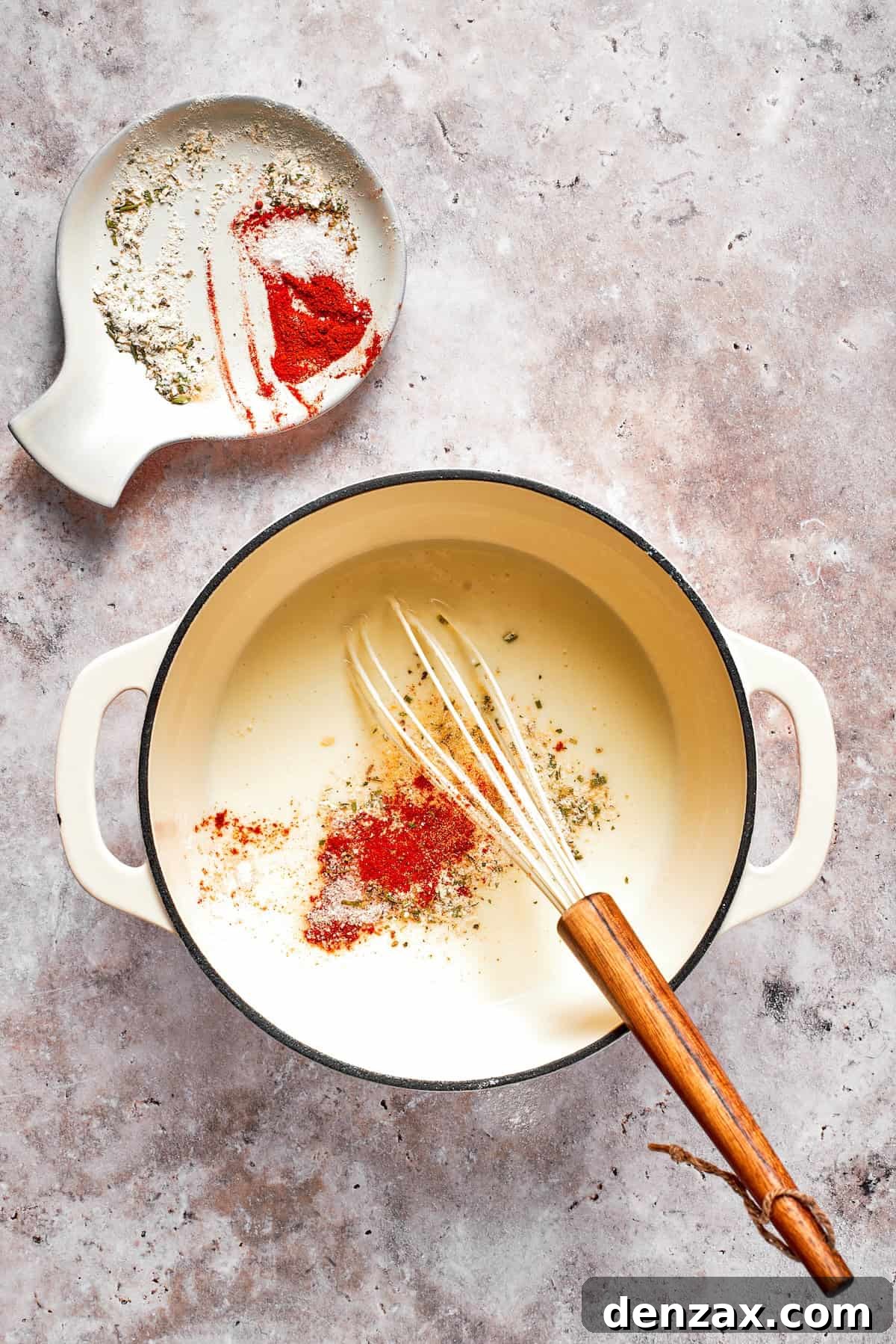 Spices are whisked into a pot of sauce.