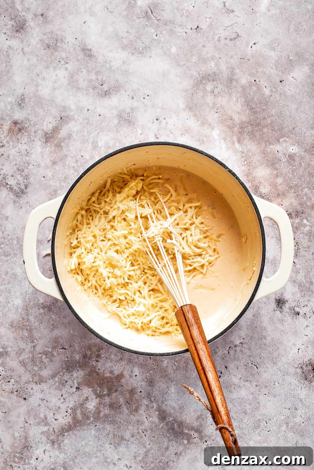 Shredded cheese is added to a pot of sauce.