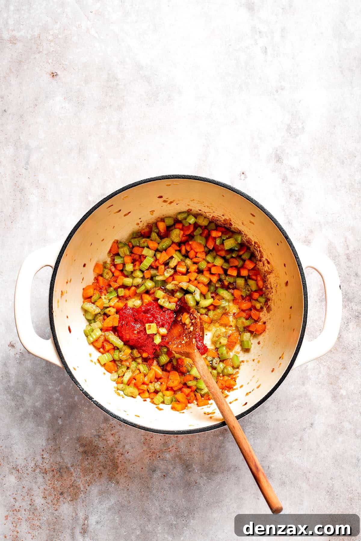 Tomato paste is sauteed with vegetables in a pot.