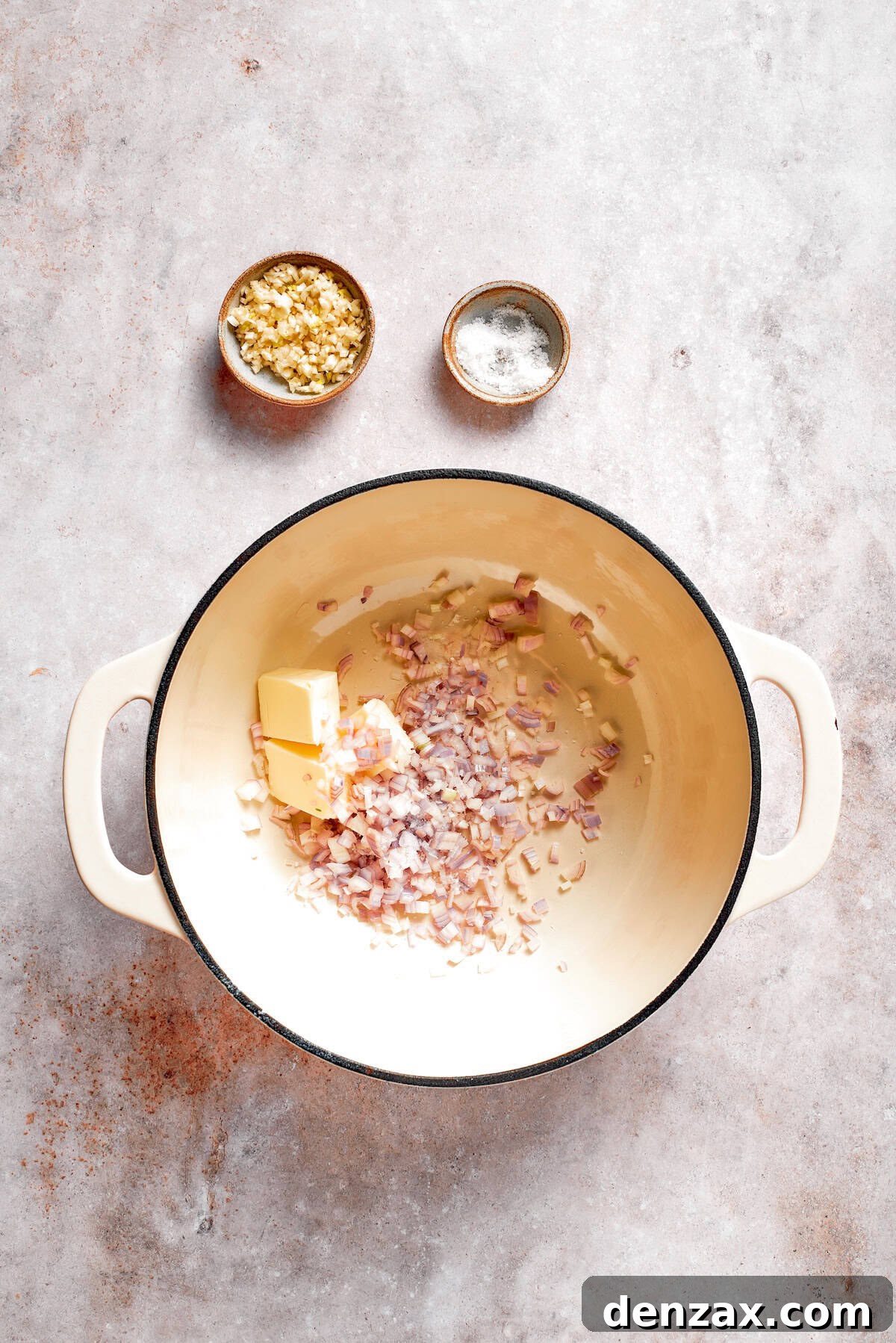 Butter and shallots cook together in a soup pot.