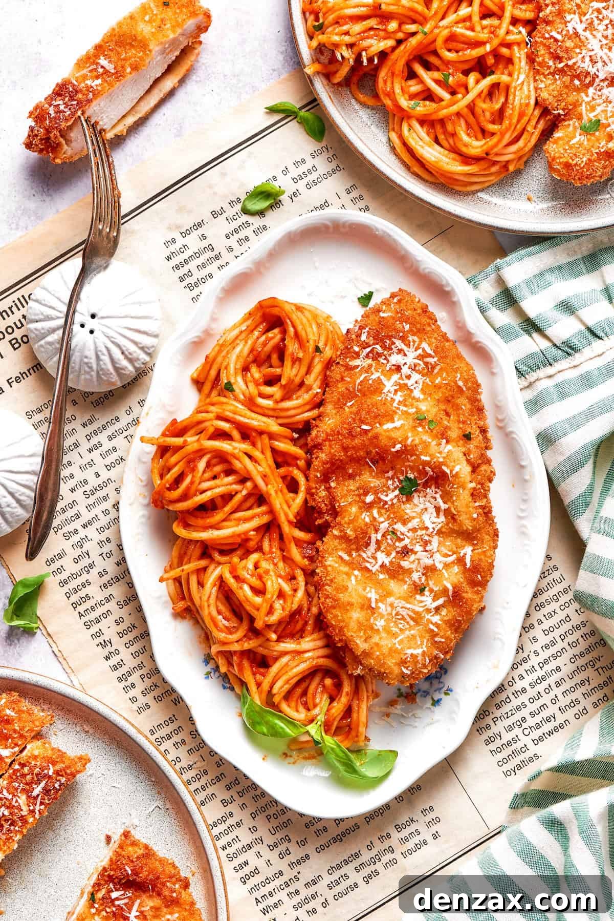 This Cheesecake Factory copycat crusted chicken romano stars crispy, breaded chicken cutlets served on pasta with marinara. A platter of spaghetti and marinara sauce and pieces of crusted chicken romano.