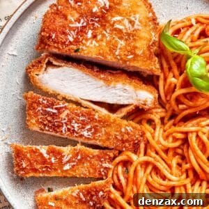 Crispy Romano-Crusted Chicken with Parmesan Herb Breading 2 A piece of crusted chicken romano sliced and served with spaghetti.