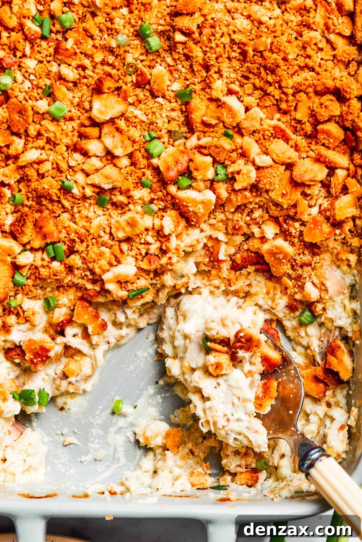 A serving spoon scoops into million dollar chicken casserole.