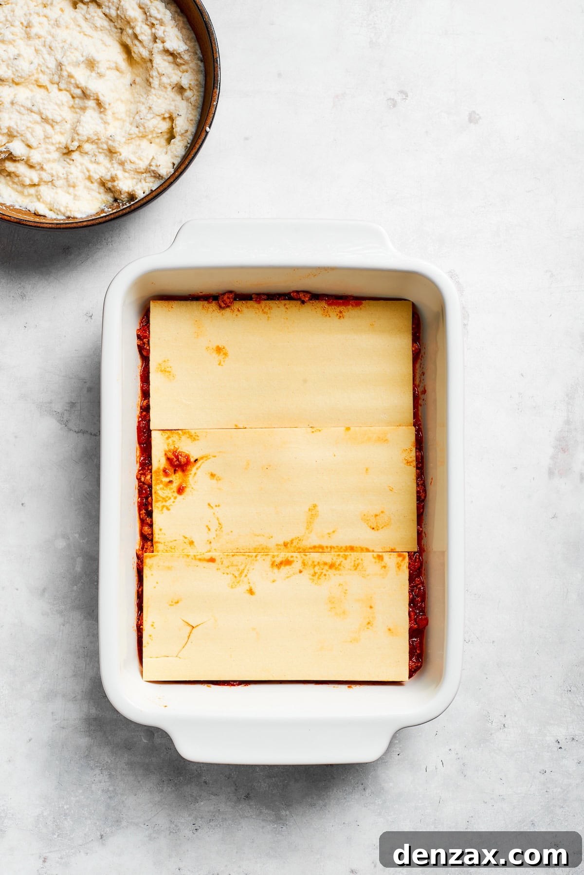 Lasagna sheets are layered in a pan.