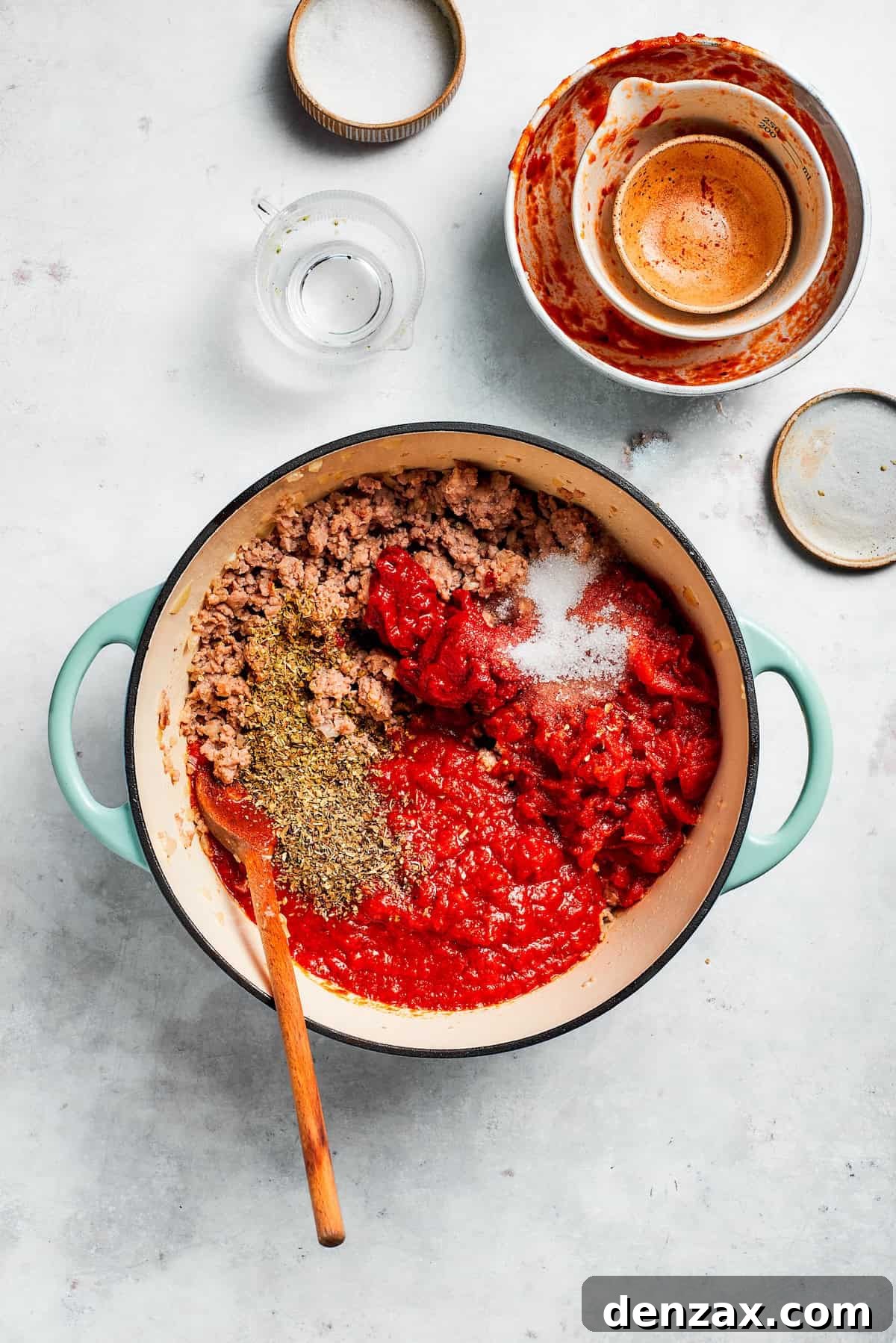 Sauce and tomato paste are added to a skillet.