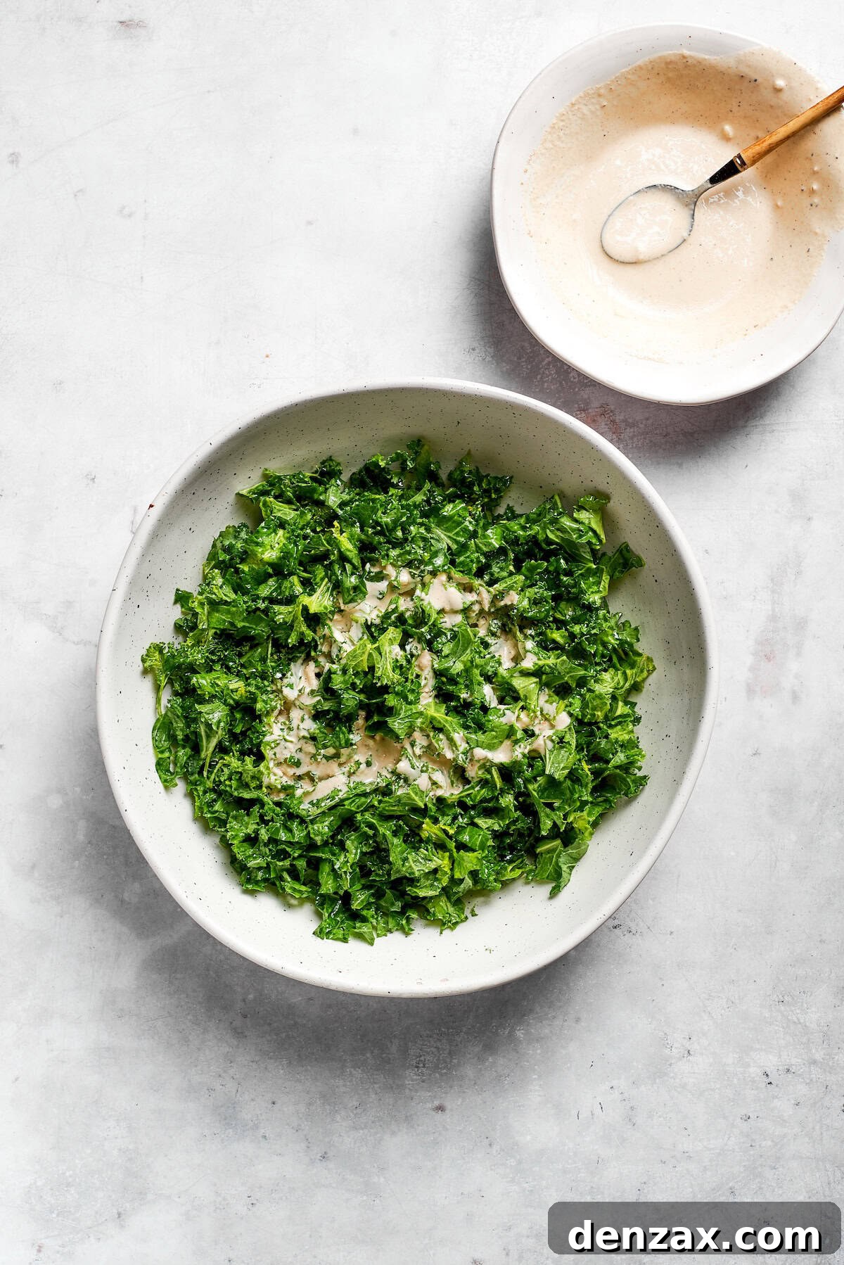 Dress the salad Dressing is added to kale caesar salad.