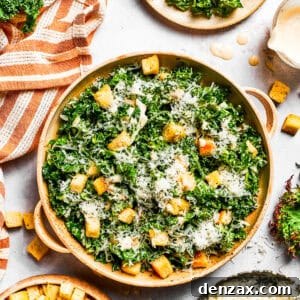 Kale Caesar Salad with Crispy Homemade Croutons 2 A large bowl of kale Caesar salad garnished with homemade croutons and shredded cheese.