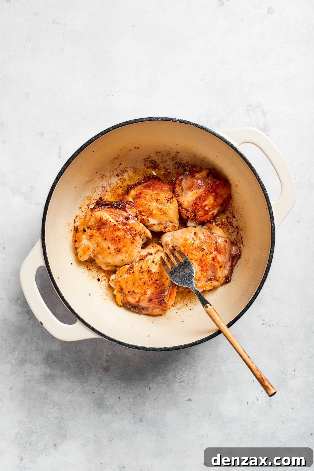 A fork moves chicken in a pot.