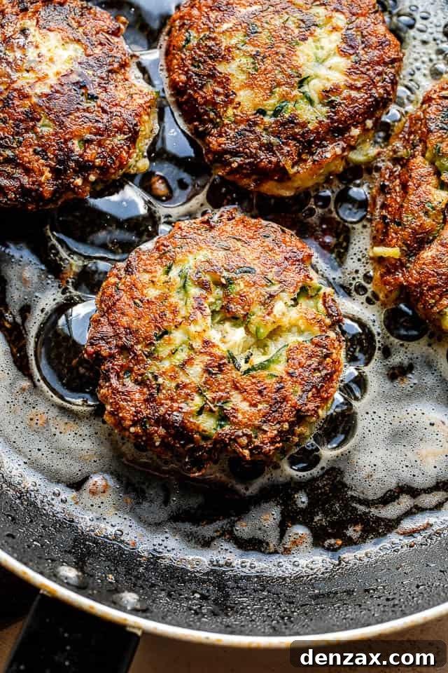 frying zucchini patties in a black colored skillet