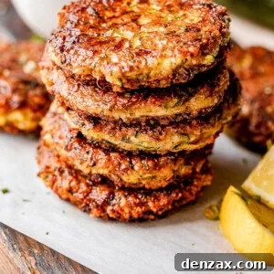 stacked zucchini patties with lemon wedges next to them and yogurt dip behind