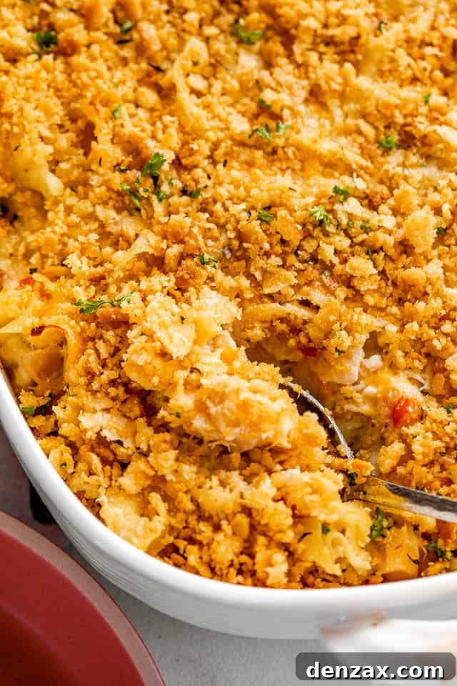 silver spoon cutting into a tuna noodle casserole topped with ritz crackers