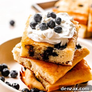 Sheet-Pan Pancakes Recipe: Fluffy Oven-Baked Pancake Tray 6 side shot of stacked sheet pan pancakes topped with whipped cream and blueberries