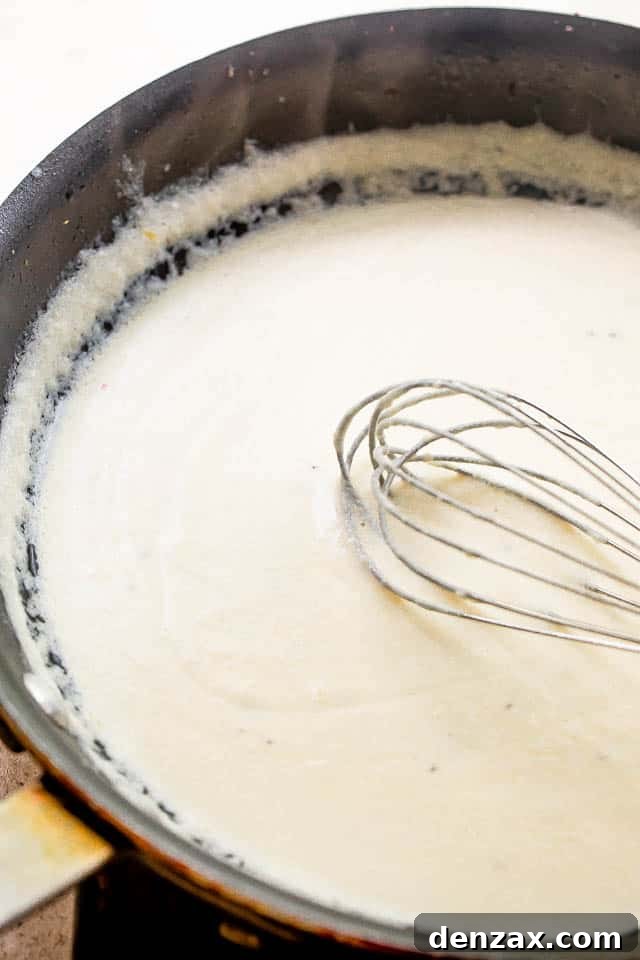 whisking cream cheese sauce in a black skillet