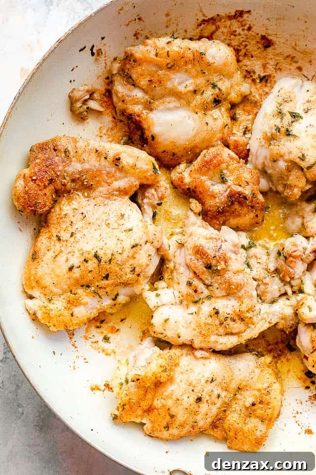 Cream Sauce Chicken Thighs features pan-seared boneless chicken thighs smothered in a decadent cream cheese sauce and topped with bacon! overhead shot of boneless skinless chicken thighs in a white skillet