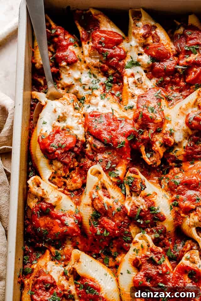Stuffed pasta shells with a savory beef and ricotta filling, baked in marinara and topped with melted cheese. It’s like lasagna in shells! close up top view of pasta shells stuffed with beef and topped with shredded cheese and marinara