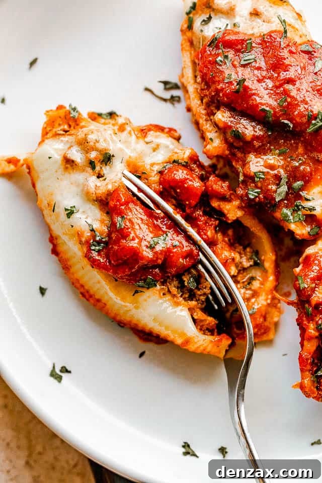 Stuffed pasta shells with a savory beef and ricotta filling, baked in marinara and topped with melted cheese. It’s like lasagna in shells! cutting into stuffed pasta shells with a fork