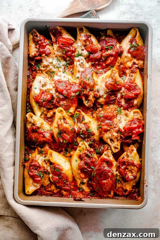Stuffed pasta shells with a savory beef and ricotta filling, baked in marinara and topped with melted cheese. It’s like lasagna in shells! overhead shot of baked pasta shells stuffed with lasagna mixture of beef and cheese.
