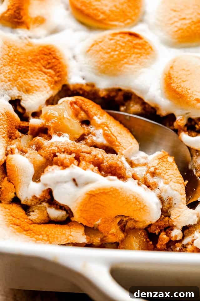 cutting into marshmallow topped apple crumble with a serving spoon