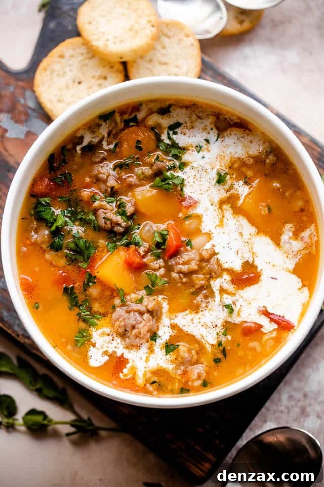 Overhead shot of butternut squash and sausage soup served in a white bowl.