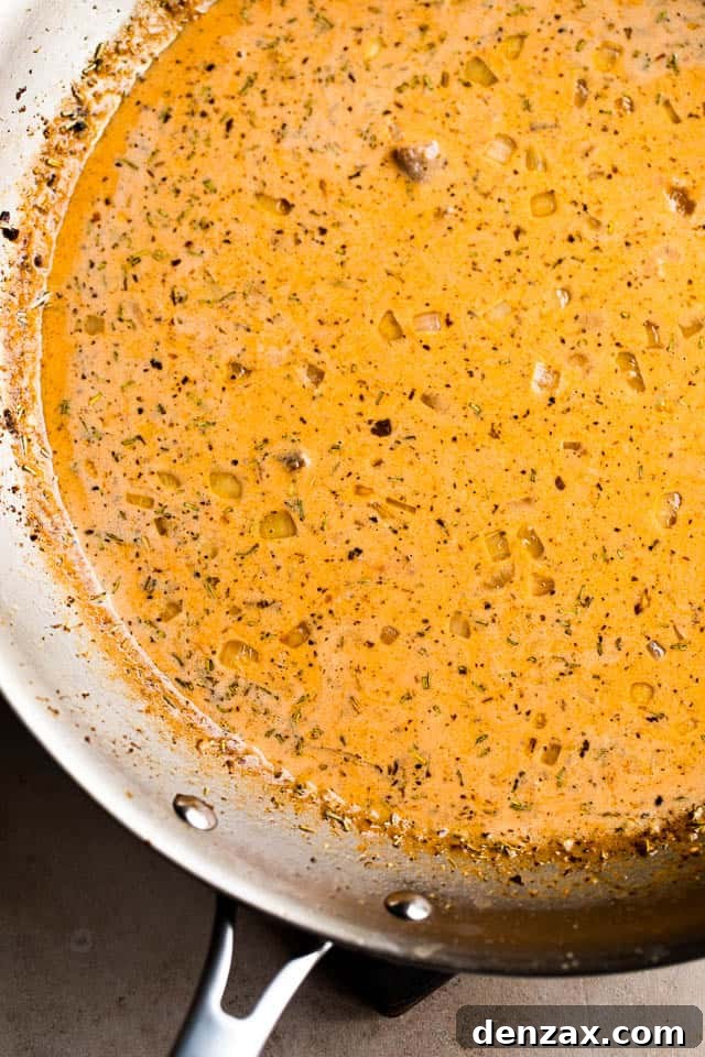 cooking creamy tomato sauce in a stainless steel skillet