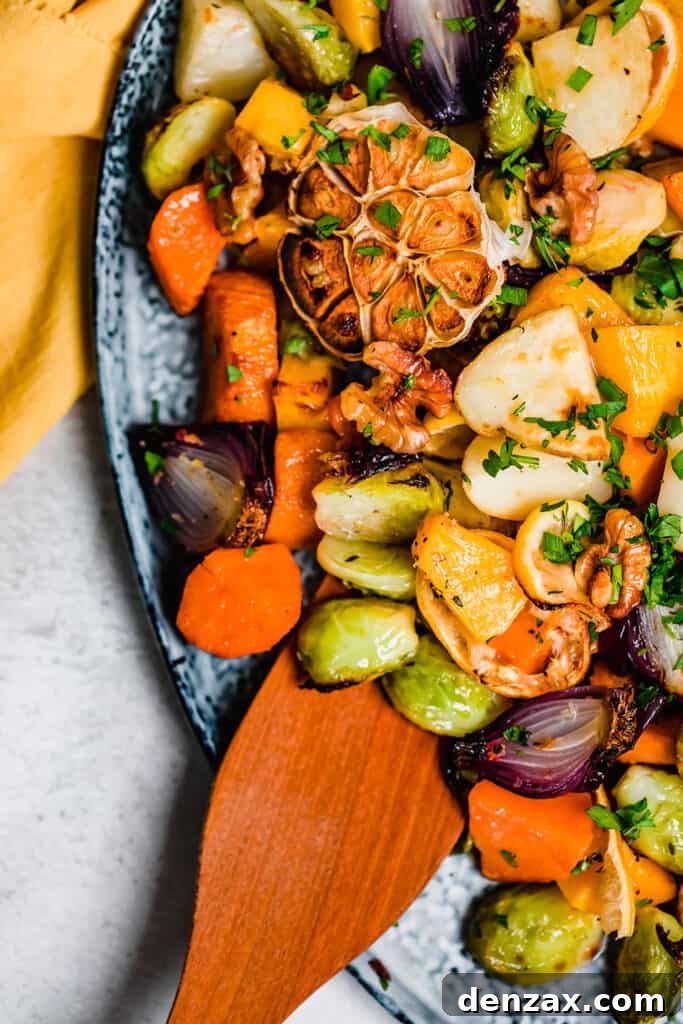 Crispy Oven-Roasted Vegetables with Garlic and Herbs 8 A wooden spoon resting on roasted vegetables on a blue platter.
