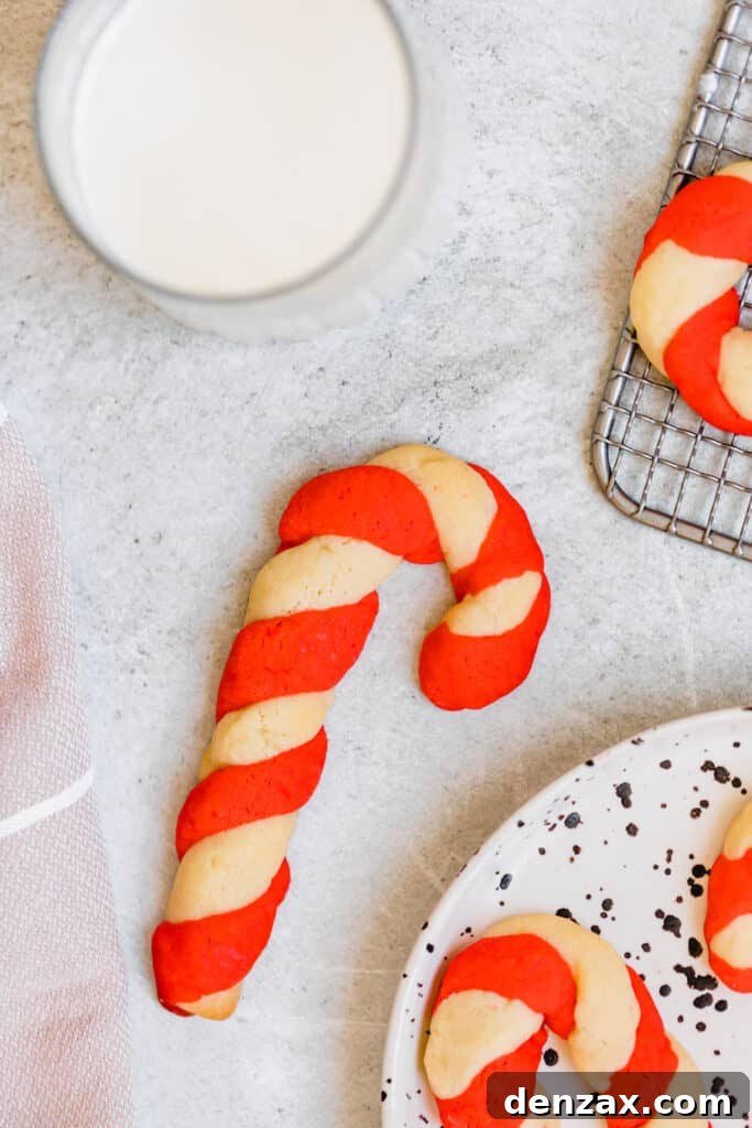 A Single Cookie on the Counter Next to a Plate Holding More Candy Cane Cookies