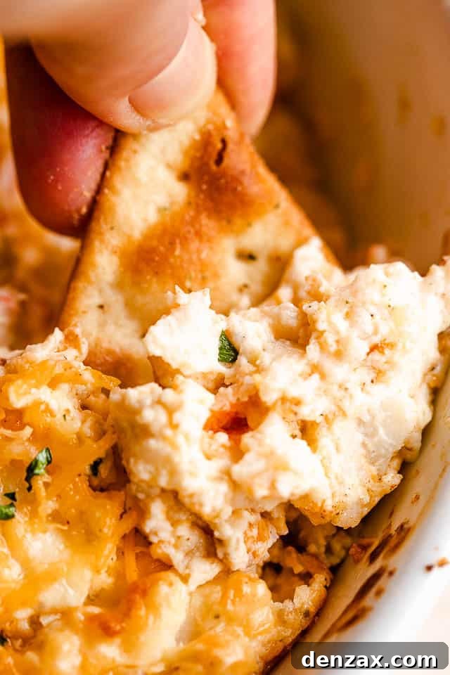 dipping into hot crab dip with pita chip