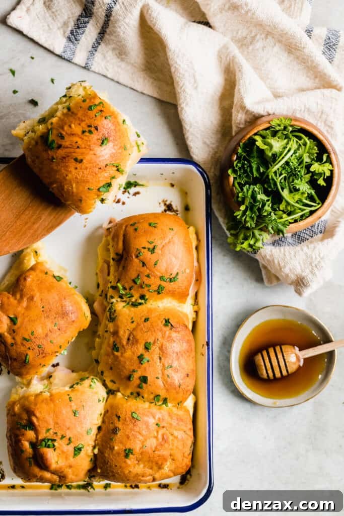 Ham and Swiss Sliders with Honey-Mustard Glaze 4 A Pan Full of Ham Sandwiches Beside a Small Bowl of Fresh Honey