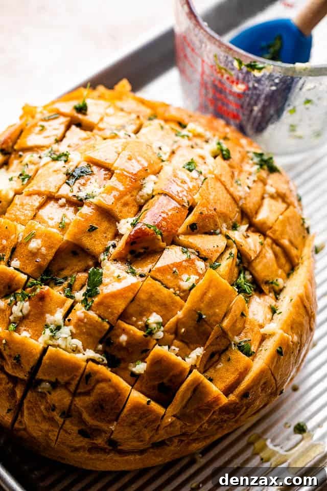 crosshatched loaf of bread with melted butter, garlic, and parsley