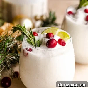 drinking glass filled with margaritas and garnished with lime slices, rosemary sprigs, and cranberries
